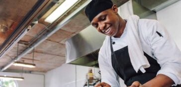 Chef at restaurant spooning vegetables